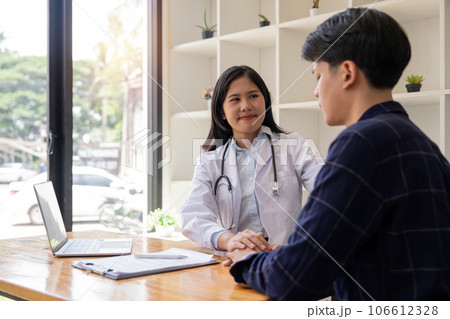 Female doctor giving encouragement to male patient by holding hand and a shoulder tap 106612328