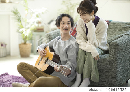 ソファーに座ってギターを弾きながら歌う若いカップル 106612525