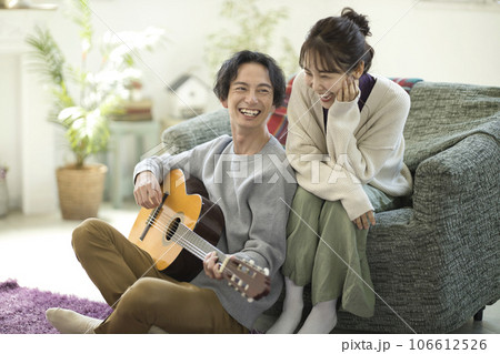ソファーに座ってギターを弾きながら歌う若いカップル 106612526