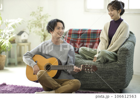 ソファーに座ってギターを弾きながら歌う若いカップル 106612563