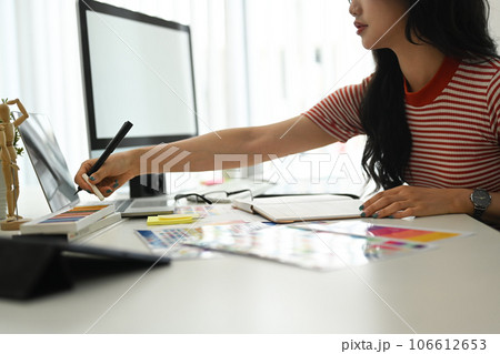 Creative woman using digital tablet and working with choosing color samples on desk at graphic studio Creative woman using digital tablet and working with choosing color samples on desk at graphic studio 106612653
