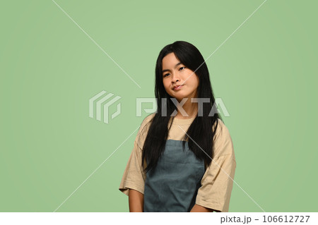 Asian teenage girl wearing apron standing against on green background Asian teenage girl wearing apron standing against on green background 106612727