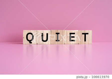 Wooden blocks form the text "QUIET" against a pink background. 106613970