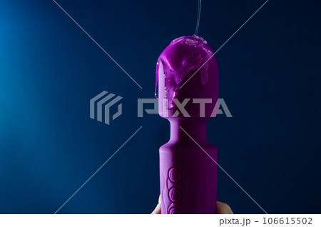 Intimate lubricant pours on a purple vibrator on a blue background. Copy space.  106615502