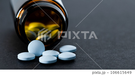 Pill bottle spilling out blue pills, copy space, space for text. Pill bottle spilling out blue pills, copy space, space for text. 106615649