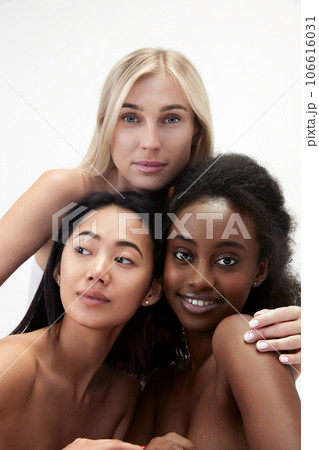 Portrait of beautiful, young asian, caucasian and african tender women with well-kept smooth skin standing against white background 106616031