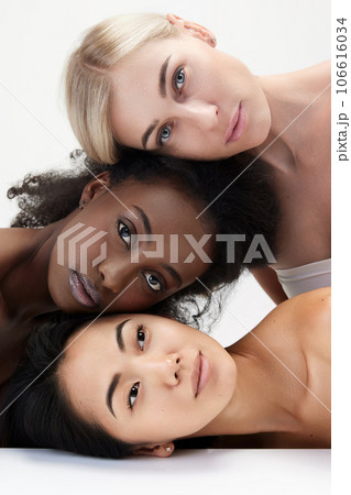 Portrait of three multiracial young women with perfect skin standing against white background against white background Portrait of three multiracial young women with perfect skin standing against white background against white background 106616034