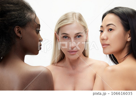 Multiracial beauty. Three young asian, caucasian and african tender women standing against white background Multiracial beauty. Three young asian, caucasian and african tender women standing against white background 106616035