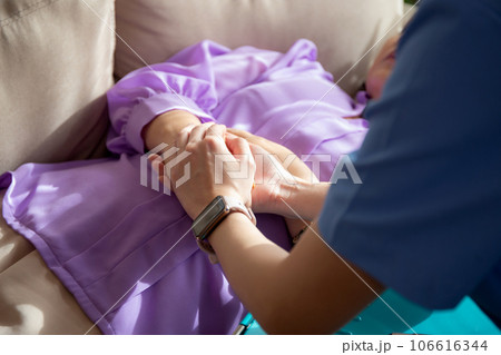 Closeup hands caregiver woman or doctor encourage and care senior while lying on sofa. 106616344