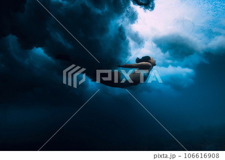 Woman dive under wave. Duck dive under crashing barrel wave in transparent ocean 106616908