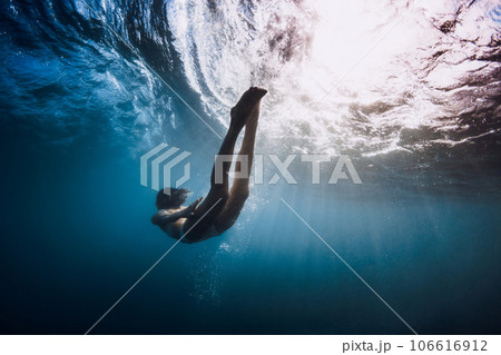 Woman underwater swim under ocean wave and sun rays. 106616912