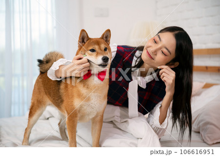 Young Asian Woman Engaging in Playtime with Her Beloved Shiba Dog in Bedroom Young Asian Woman Engaging in Playtime with Her Beloved Shiba Dog in Bedroom 106616951