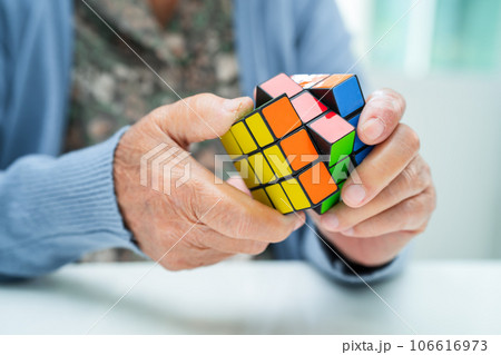 Bangkok, Thailand August 14, 2023 Alzheimer disease AD, Asian elderly woman patient playing Rubik cube game to practice brain training for dementia prevention. Bangkok, Thailand August 14, 2023 Alzheimer disease AD, Asian elderly woman patient playing Rubik cube game to practice brain training for dementia prevention. 106616973