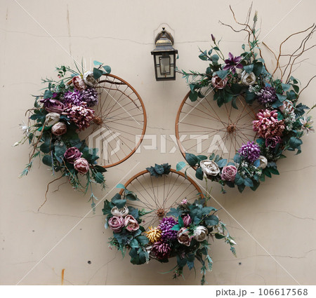 Decoration urban art object from bicycle wheels and flowers on wall Decoration urban art object from bicycle wheels and flowers on wall 106617568