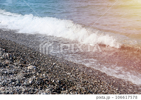 Bank of pebbles with the sea and beach in the background 106617578