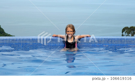 Happy little girl enjoying bathing in infinity pool by the beautiful blue sea Happy little girl enjoying bathing in infinity pool by the beautiful blue sea 106619316