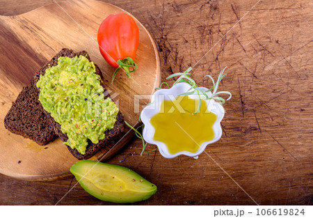Olive oil, tomato, bread with avocado on wood cutting board. Olive oil, tomato, bread with avocado on wood cutting board. 106619824