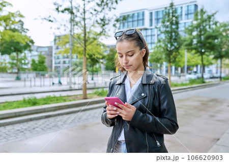 Portrait of young teenage female with smartphone, on street of modern city Portrait of young teenage female with smartphone, on street of modern city 106620903