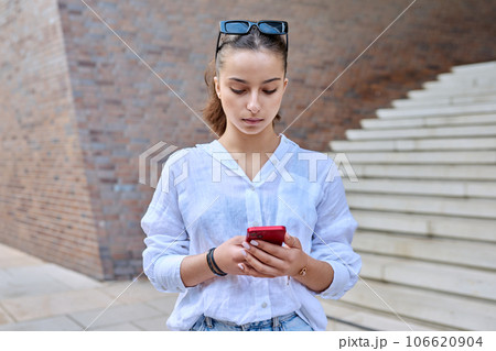 Portrait of young teenage female with smartphone, on street of modern city 106620904