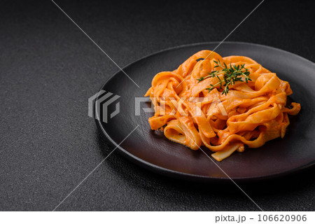 Delicious fresh pasta with pesto sauce, salt, spices and herbs on a ceramic plate Delicious fresh pasta with pesto sauce, salt, spices and herbs on a ceramic plate 106620906
