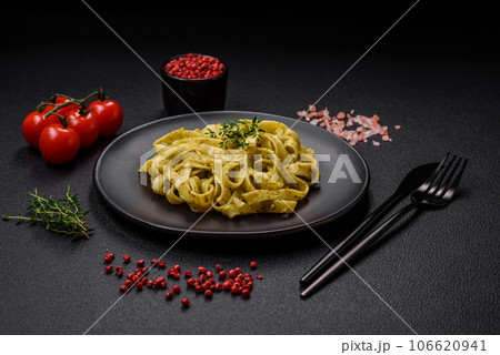 Delicious fresh pasta with pesto sauce, salt, spices and herbs on a ceramic plate Delicious fresh pasta with pesto sauce, salt, spices and herbs on a ceramic plate 106620941