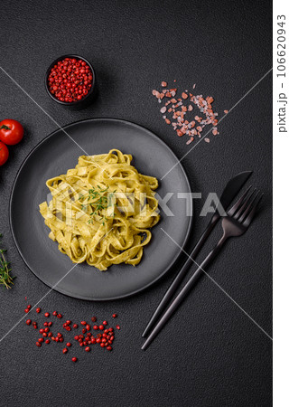 Delicious fresh pasta with pesto sauce, salt, spices and herbs on a ceramic plate 106620943