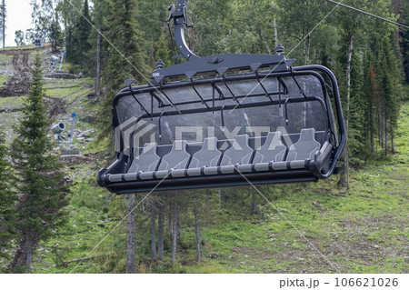 Close-up of a chairlift cab on the background of mountains and forests. Cable car trip to viewpoints in the mountains. During the trip by cable car Tourists enjoy views and experience exciting. 106621026