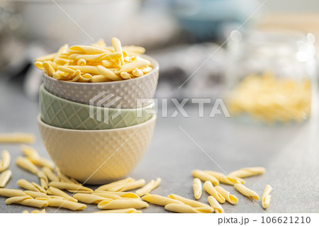Fusilli pugliesi. Italian twisted pasta in bowl on gray table. Fusilli pugliesi. Italian twisted pasta in bowl on gray table. 106621210