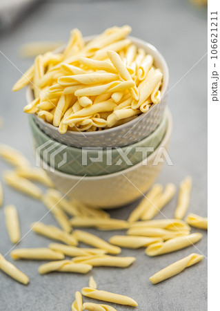 Fusilli pugliesi. Italian twisted pasta in bowl on gray table. Fusilli pugliesi. Italian twisted pasta in bowl on gray table. 106621211