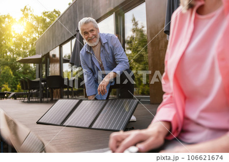 Mature couple using laptop in front of solar panels. Mature couple using laptop in front of solar panels. 106621674