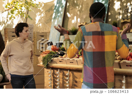 Female vegetarian shopping at local farmers market to buy natural eco produce. Customer putting fresh organic seasonal fruits and vegetables in cardboard box, buying healthy locally-grown products. Female vegetarian shopping at local farmers market to buy natural eco produce. Customer putting fresh organic seasonal fruits and vegetables in cardboard box, buying healthy locally-grown products. 106623413