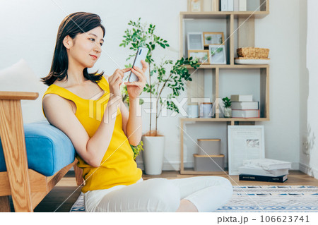 部屋でスマホを見る女性 106623741