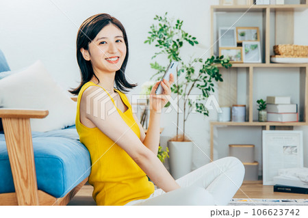 部屋でスマホを見る女性 106623742