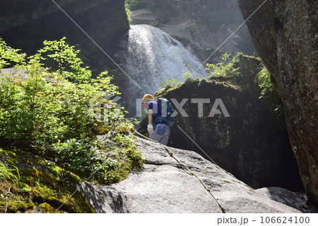 滝へと向かい岩を登る男性／登山 106624100
