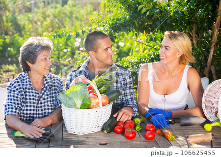 Happy family talking at wooden table in summer home garden 106625455