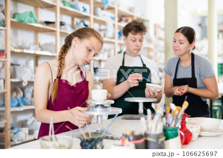 Young woman teaching teen boy and teen girl how to make ceramic cup 106625697