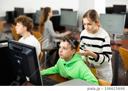 Teenage boy helping young girl with PC problem in computer class Teenage boy helping young girl with PC problem in computer class 106625698