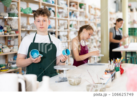 Teen boy posing with ceramic cup in ceramic workshop Teen boy posing with ceramic cup in ceramic workshop 106625749