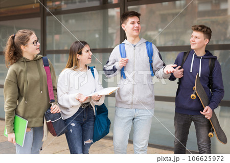 Four teenagers talking about play on walk in street Four teenagers talking about play on walk in street 106625972