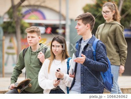 Four teenagers talking about play on walk in street Four teenagers talking about play on walk in street 106626062