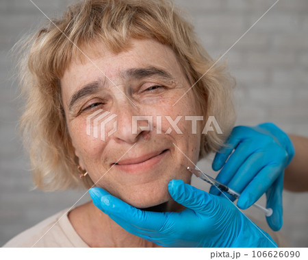 Doctor makes beauty injections in the face of an old caucasian woman.  106626090