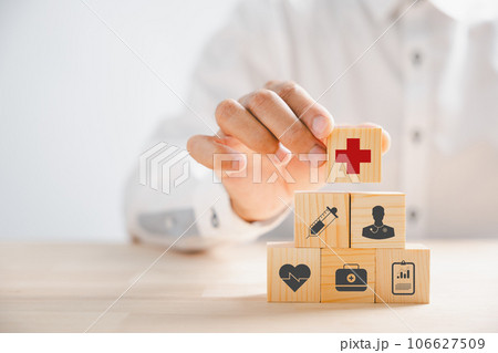 Hand grasps wooden block with healthcare and medical icons, symbolizing safety, health, and family well-being. Embodying pharmacy, heart care, and happiness concepts. health care concept 106627509