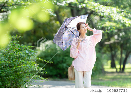 日傘を刺して歩くシニアの女性 日傘を刺して歩くシニアの女性 106627732