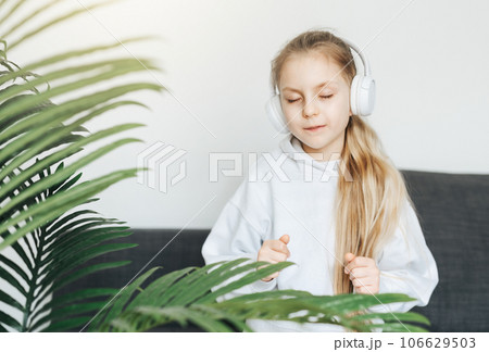 Cute little girl listening to music in headphones 106629503