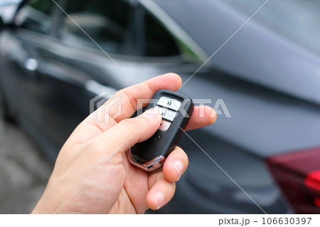 The man in the hand held the remote control of the car, he opened the remote control of the car door. To drive a car 106630397