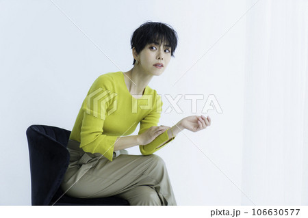 白背景の椅子に座る若い女性のファッションポートレート 106630577