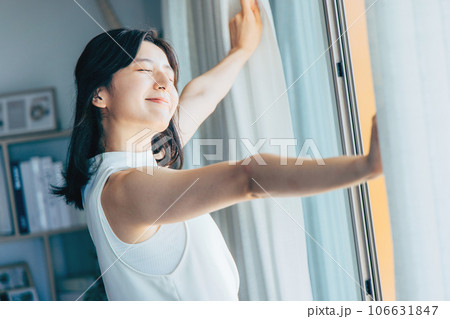 カーテンを開けて朝日を浴びる女性 106631847