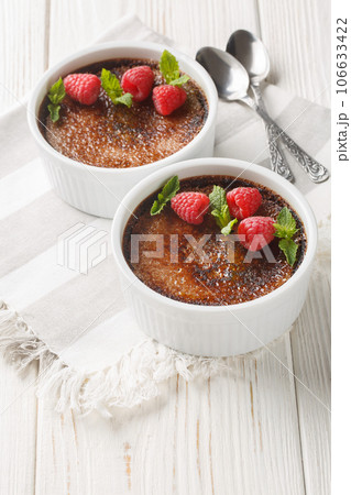 Spanish Chocolate creme brulee with caramelized sugar on top decorated with mint and raspberries close-up in a ramekin. Vertical 106633422