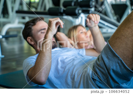 Man and woman sit up on mat in sport gym working out Man and woman sit up on mat in sport gym working out 106634052