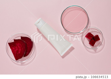 A white plastic tube unbranded displayed on a pink background with petri dishes containing slices and essence of beetroot. Mockup for design, advertising and branding cosmetic extracted from beetroot A white plastic tube unbranded displayed on a pink background with petri dishes containing slices and essence of beetroot. Mockup for design, advertising and branding cosmetic extracted from beetroot 106634513